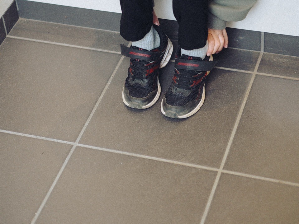 玄関で靴を脱ぐ子どものあし