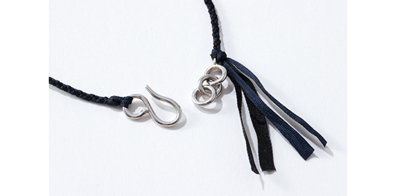 シルバーの留め具は引っかけて留めるU字のフックタイプ。フリンジのようなコード先のあしらいも、おしゃれ心をくすぐるポイント。