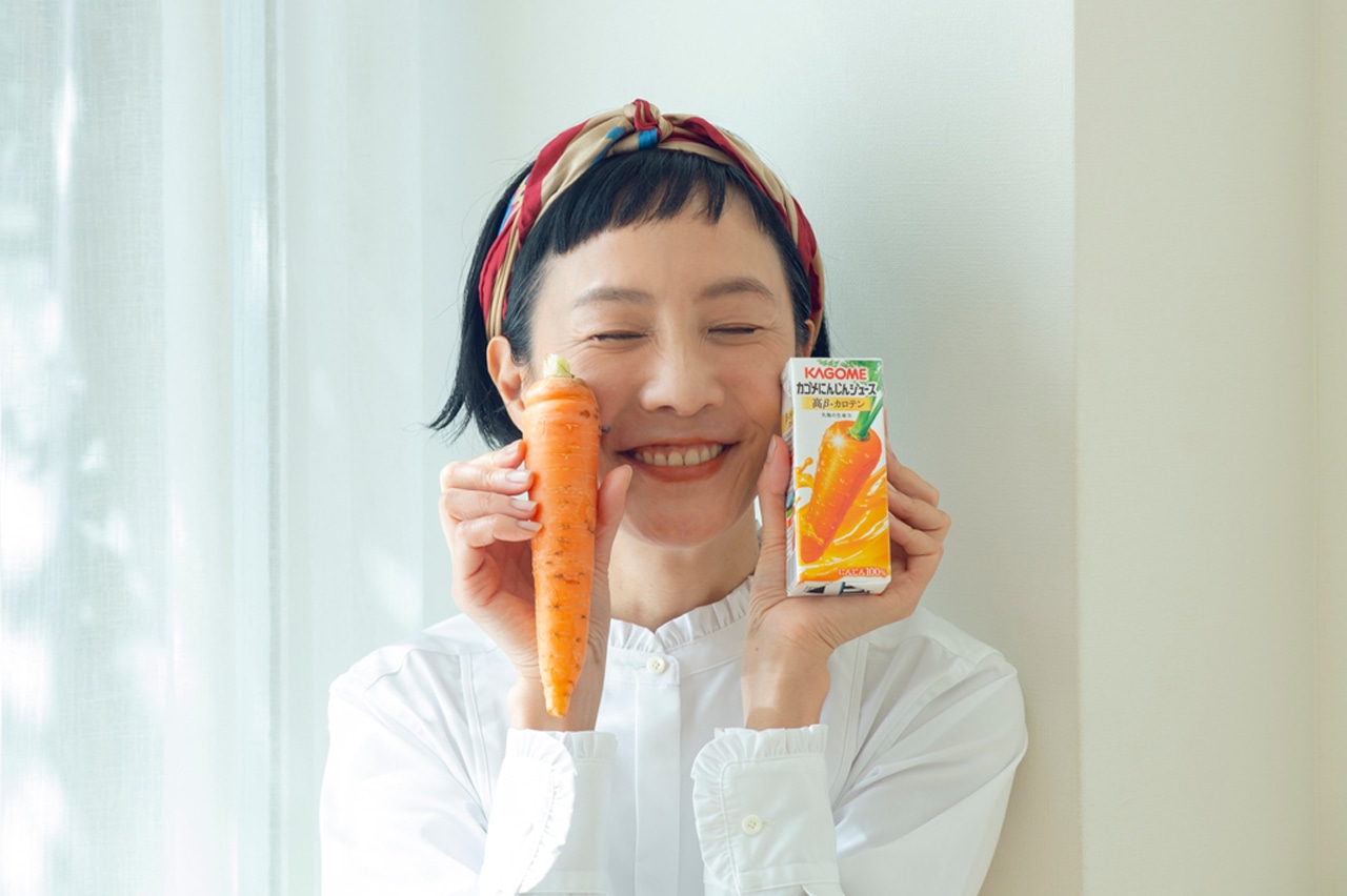 カゴメにんじんジュース高β-カロテン（パック）とにんじんを手に取るはなさん