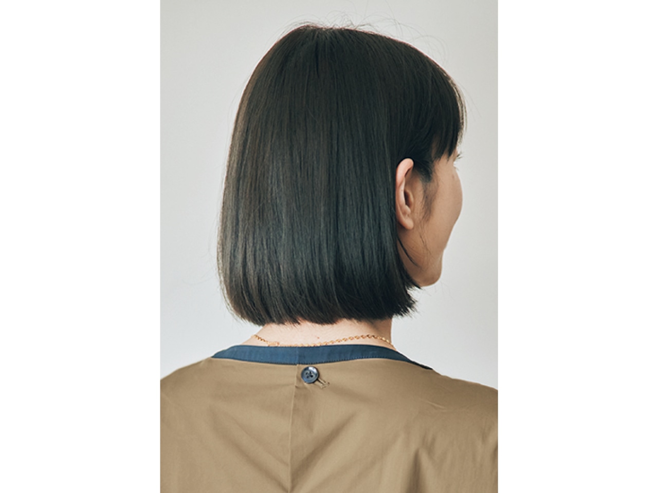 首まわりにはアクセントのパイピングを。ボタン付きで頭からすっぽり脱ぎ着できる。