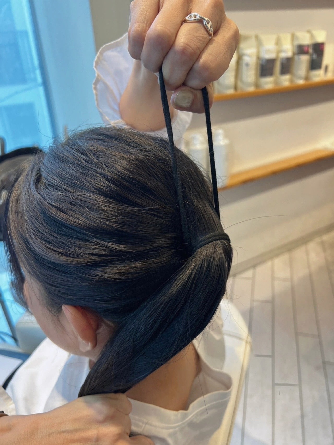 伊熊奈美さんひとつ結びアレンジのコツ ② 巻いている途中のゴムは上に輪がくるように持ち替え、引き上げながら巻き付ける。すると常に結び目の下側に圧がかかるようになる。