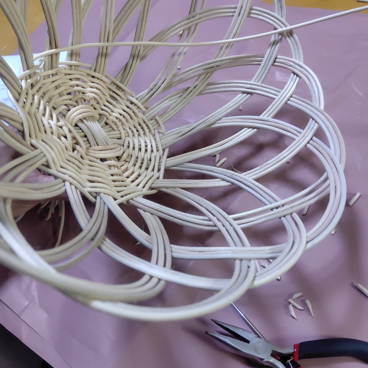 フルーツバスケットを作る工程：ラタンの束を花びらのように底部分につけていく作業（内側からのアングル）