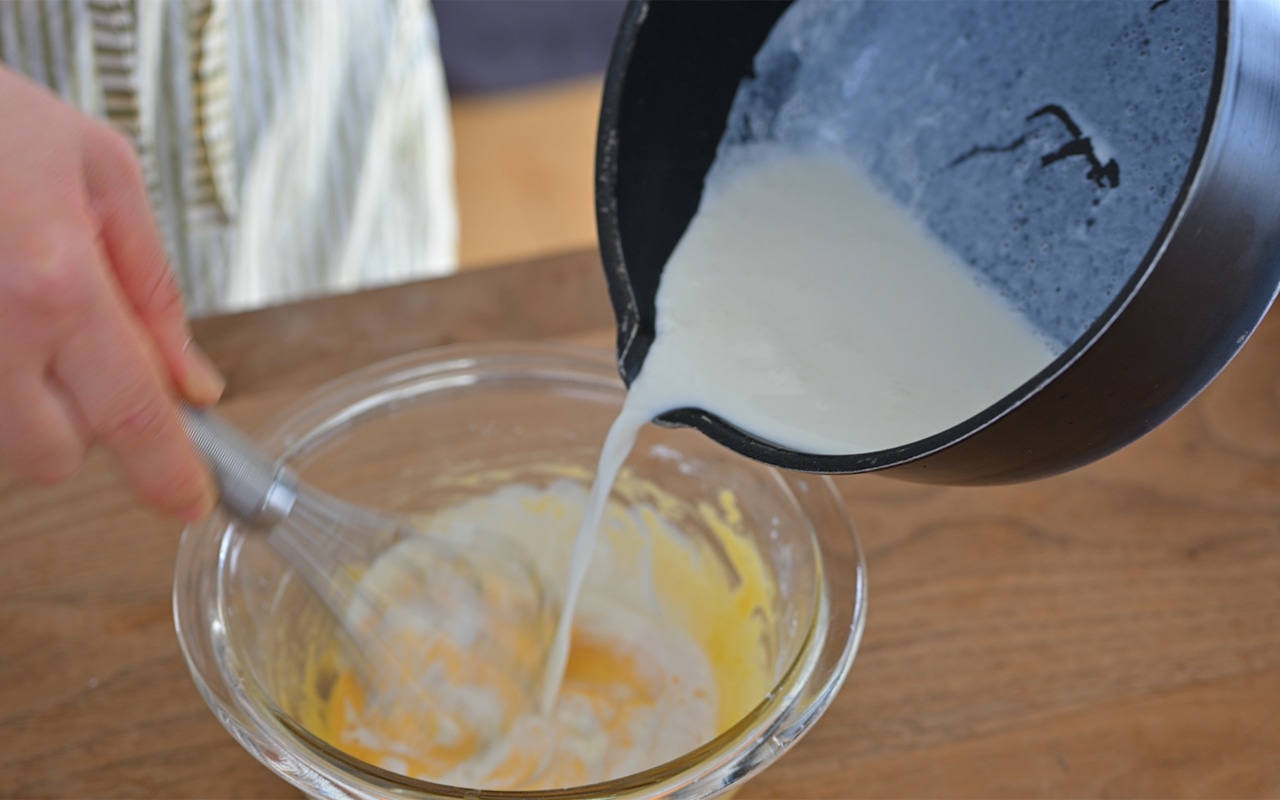 レモンの皮を取り出した①の牛乳を、②のボウルに温かいまま注ぎ入れ、泡立て器でよく混ぜる