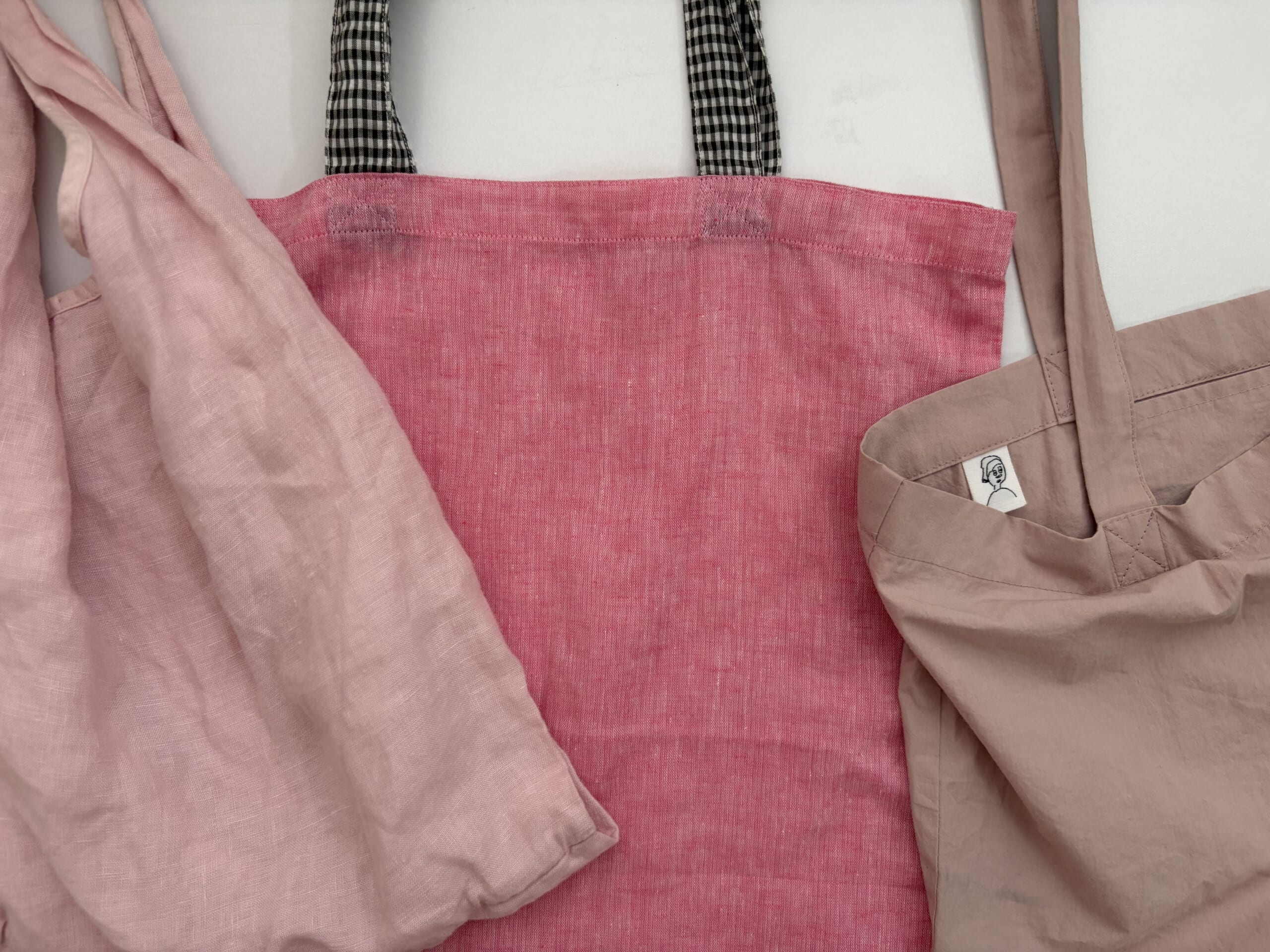 50代女性がもてるかわいいピンクのエコバッグ。左/nest Robe(ネストローブ)リネンパッカブルエコバッグSサイズ、中/nui_mond(ヌイモンド)トートバッグ/a few(ア・フュー)トートバッグ。