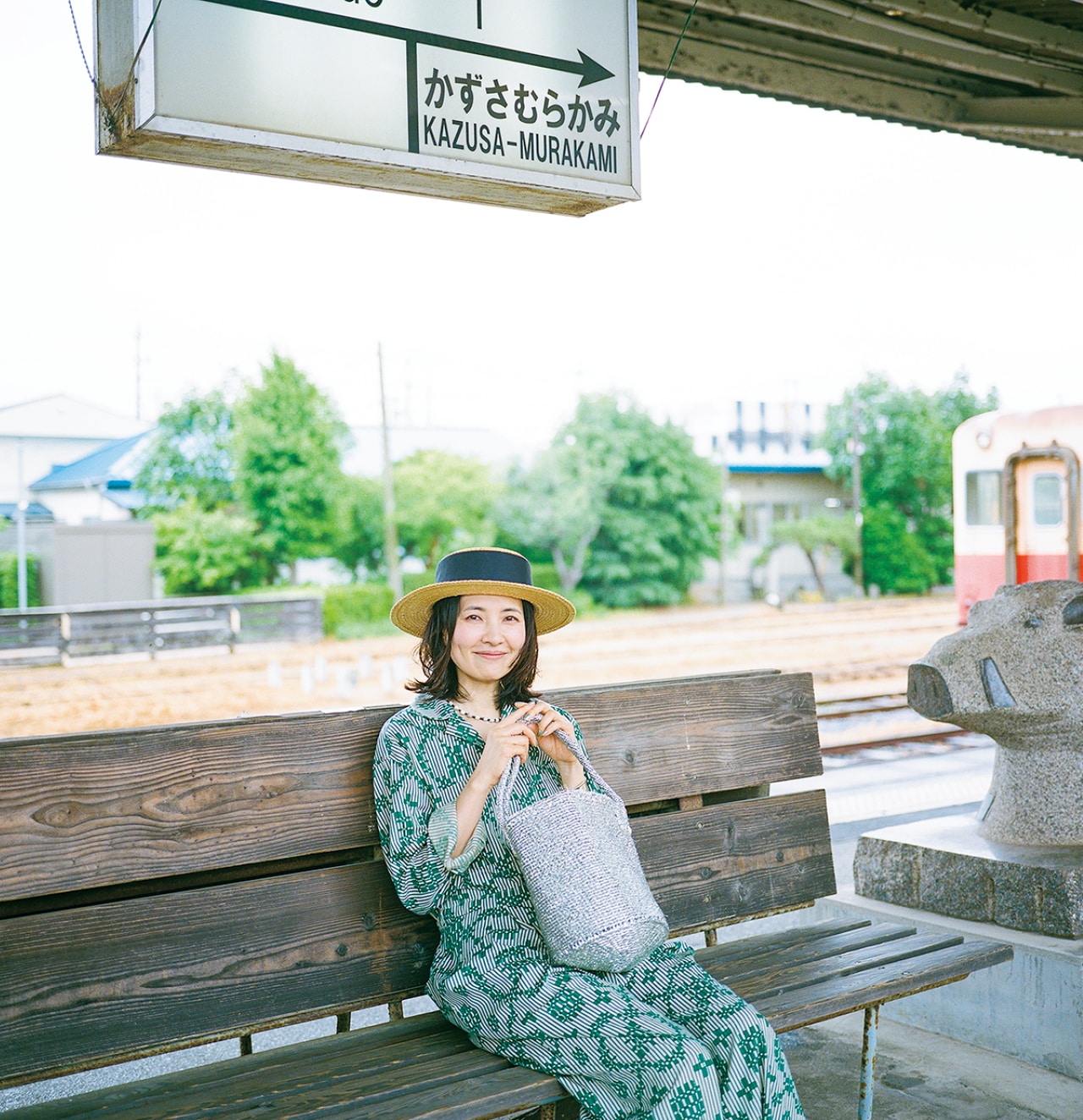 駅のホームでベンチに座って微笑む浜島直子さん