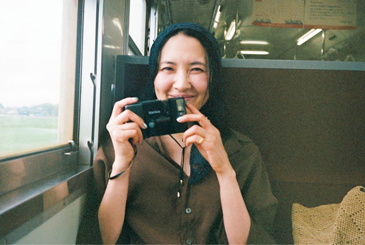 電車内でカメラを手に微笑む浜島直子さん