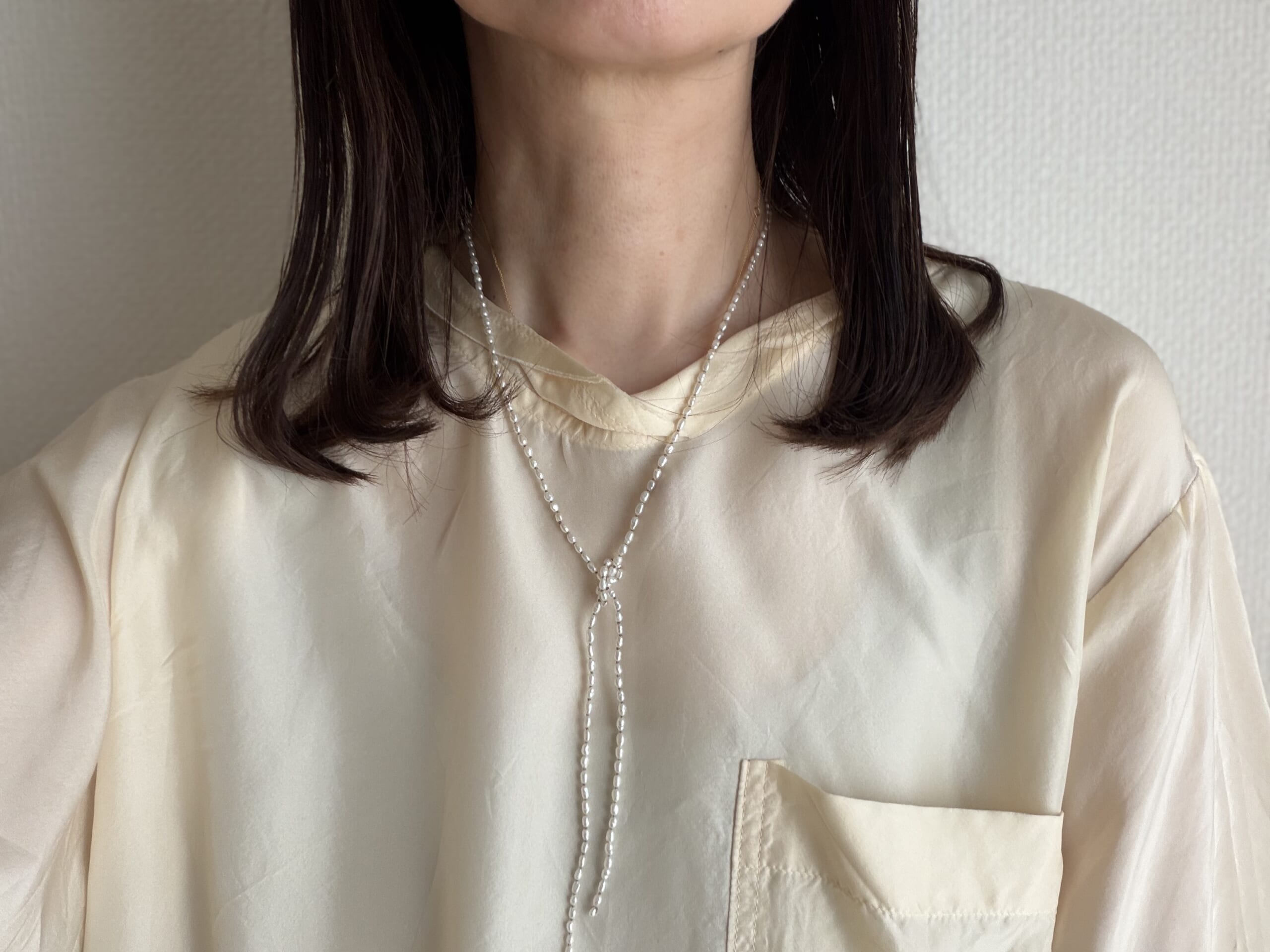 50代女性がカジュアルに身に着けたマユミムラサワのパールラリエット。結ぶだけでサマになるパールアクセサリーの着画。