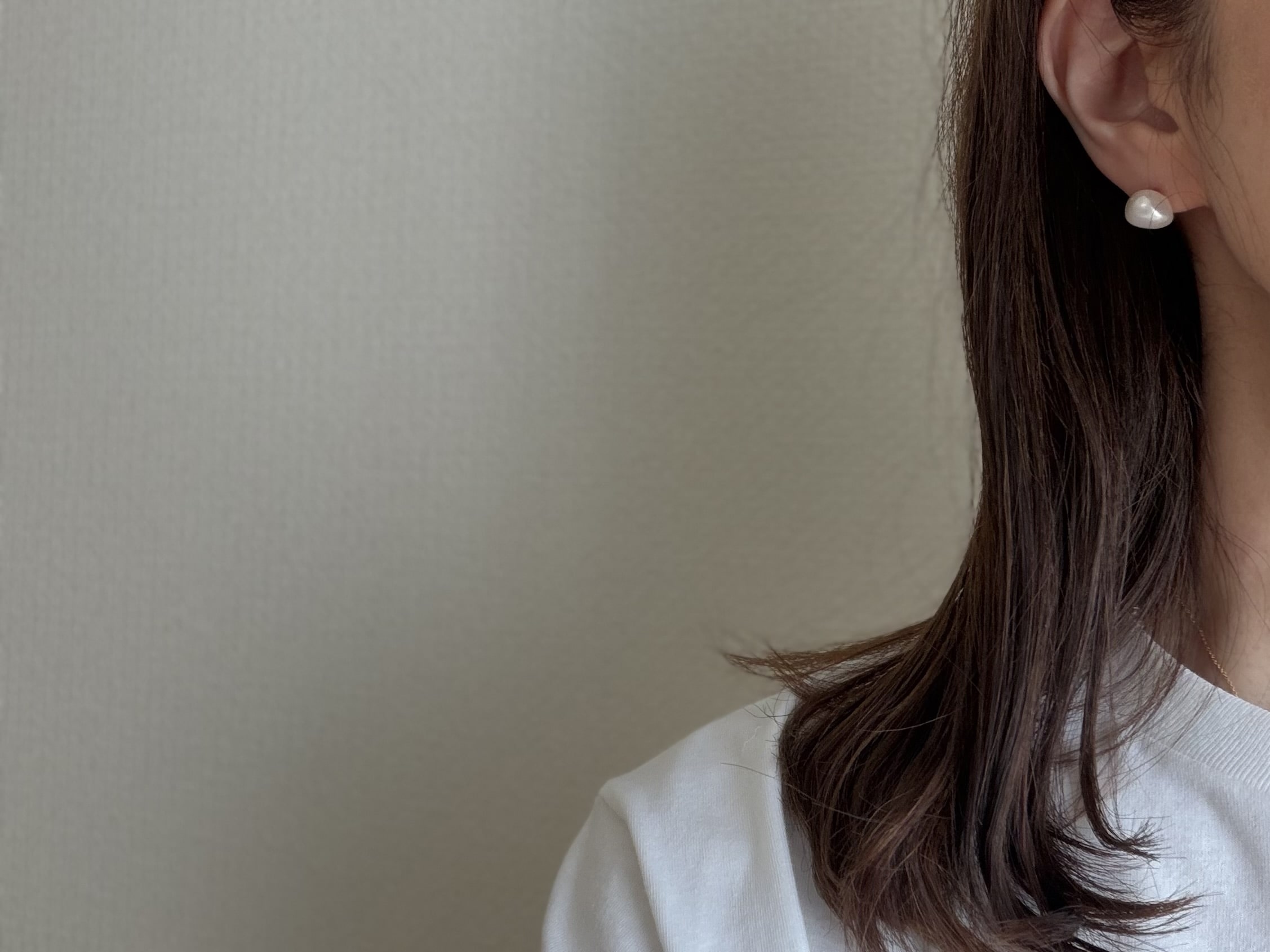 50代女性が毎日身に着けられるフォーマルすぎずカジュアルに楽しめる「大人バランス」のぷっくりいびつな形のパールのピアスの着画。