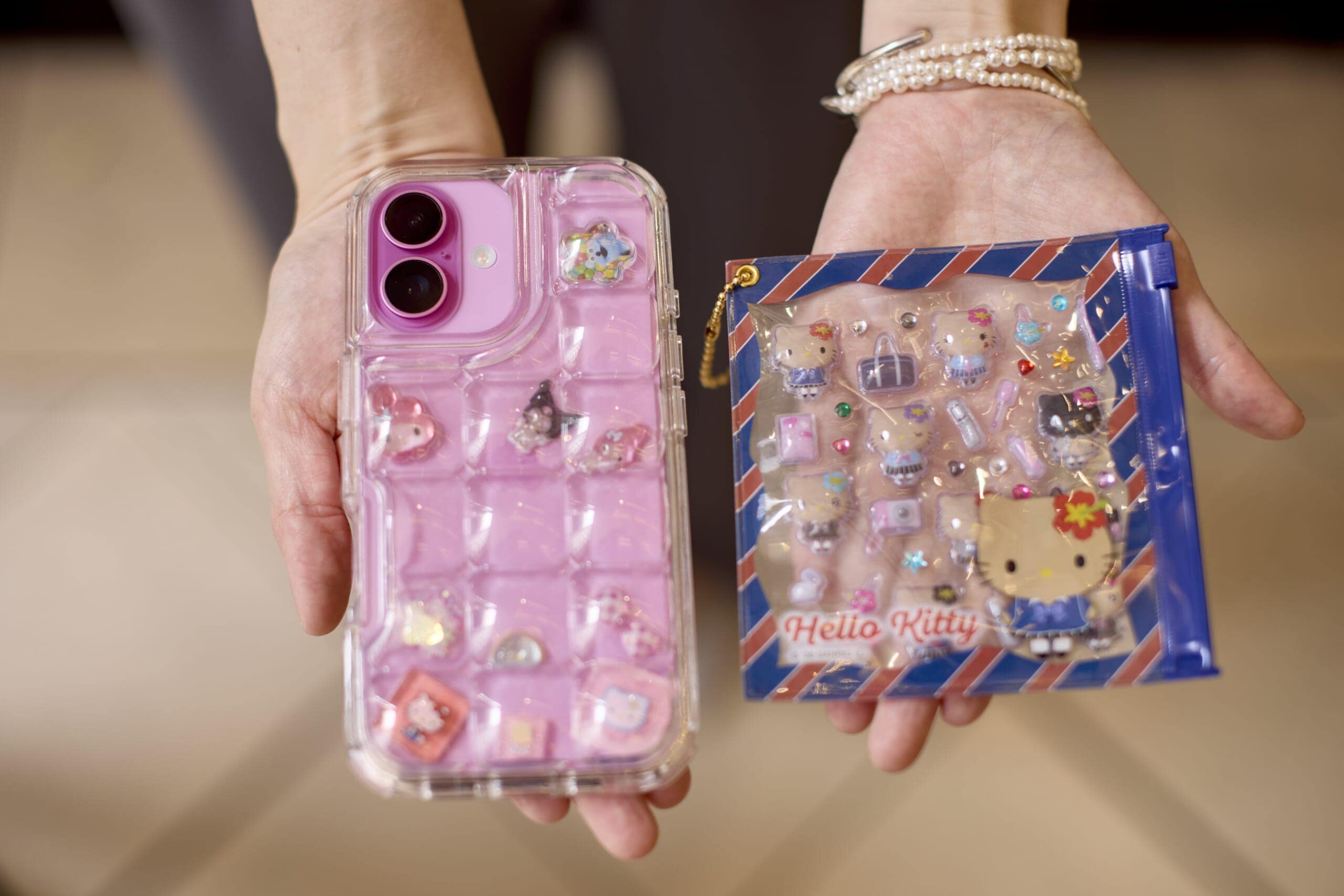ハローキティのぷっくりシールを入れたスマホケースと青いジップケース