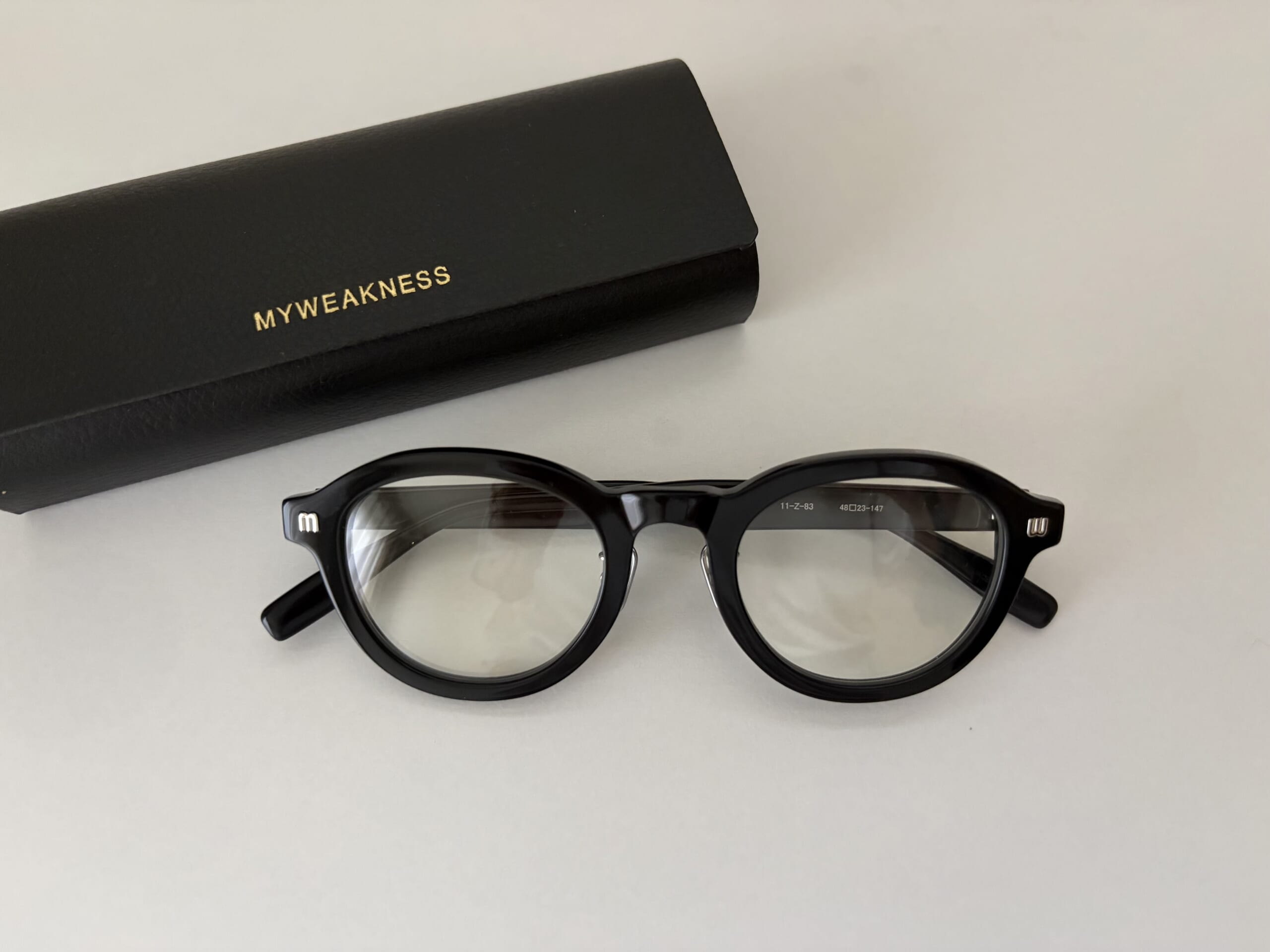 ともさかりえのブランドMY WEAKNESSの大人気メガネを置き撮りした写真。50代の顔になじむ上品で軽やかなフレームがわかるカット