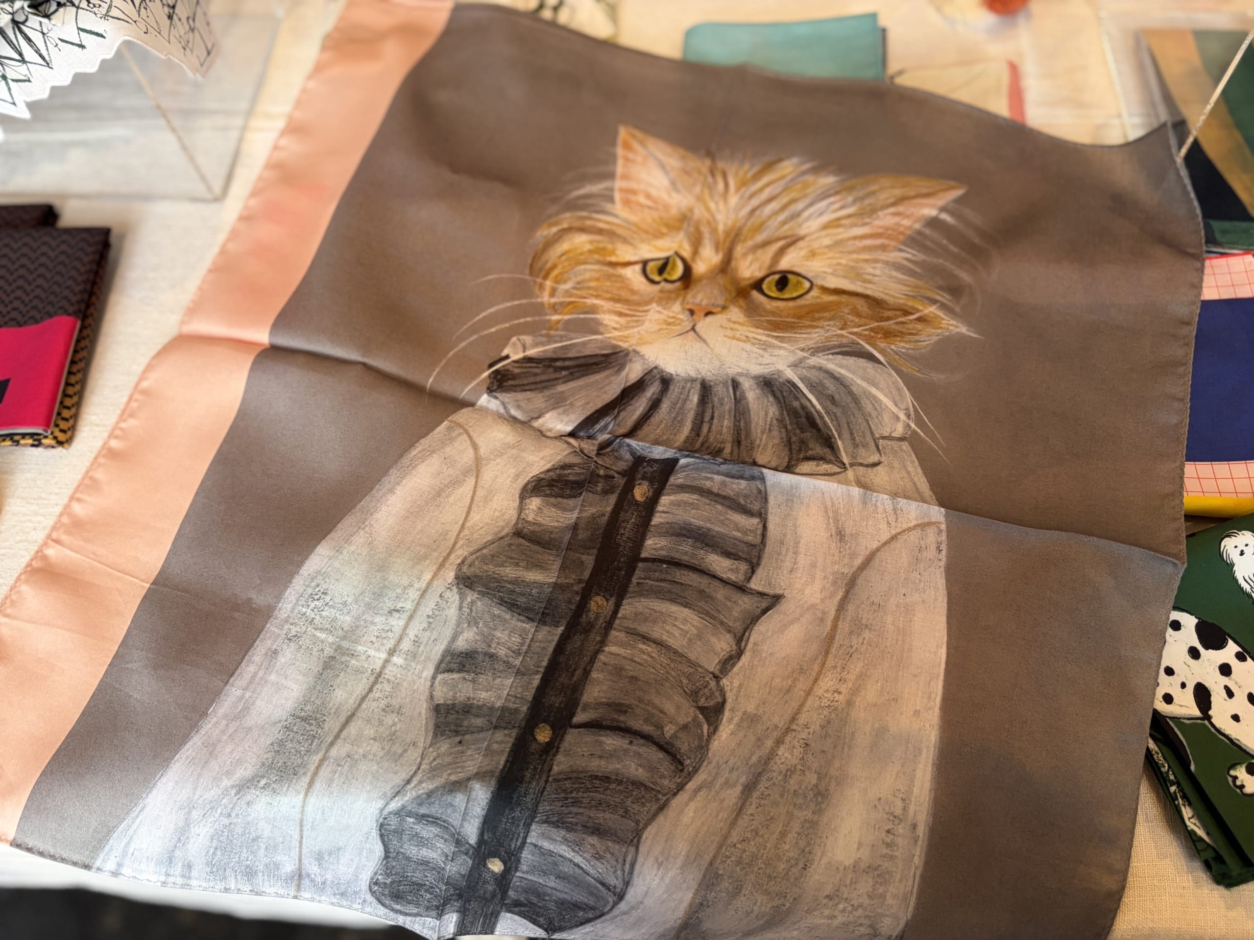 松尾ミユキ×neco.tenの『neco ねこ』絵画のような猫のイラストのハンカチをひろげたところ。