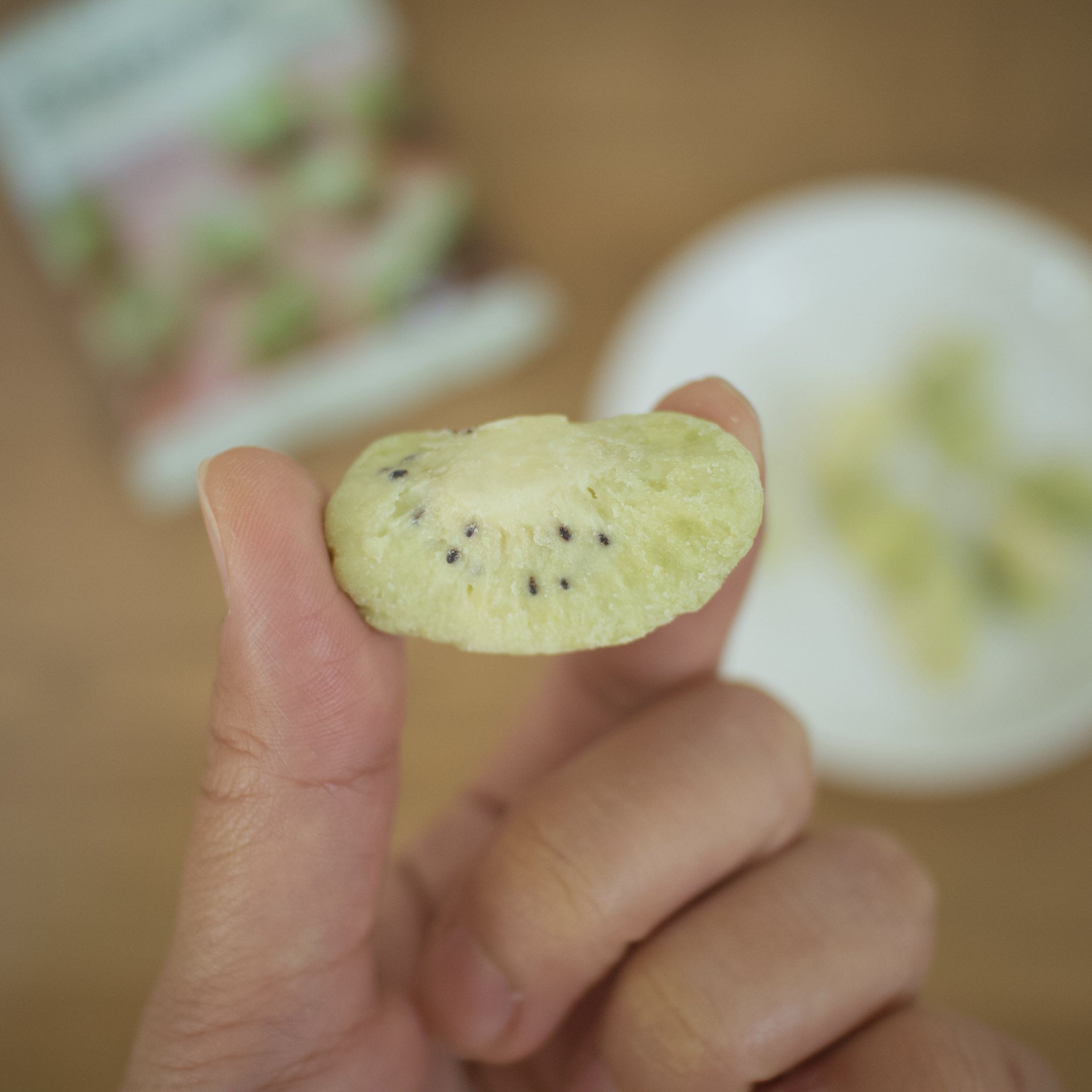 無印良品「不揃い しみこみチョコ キウイ」の種が見える一粒を指で持つ様子