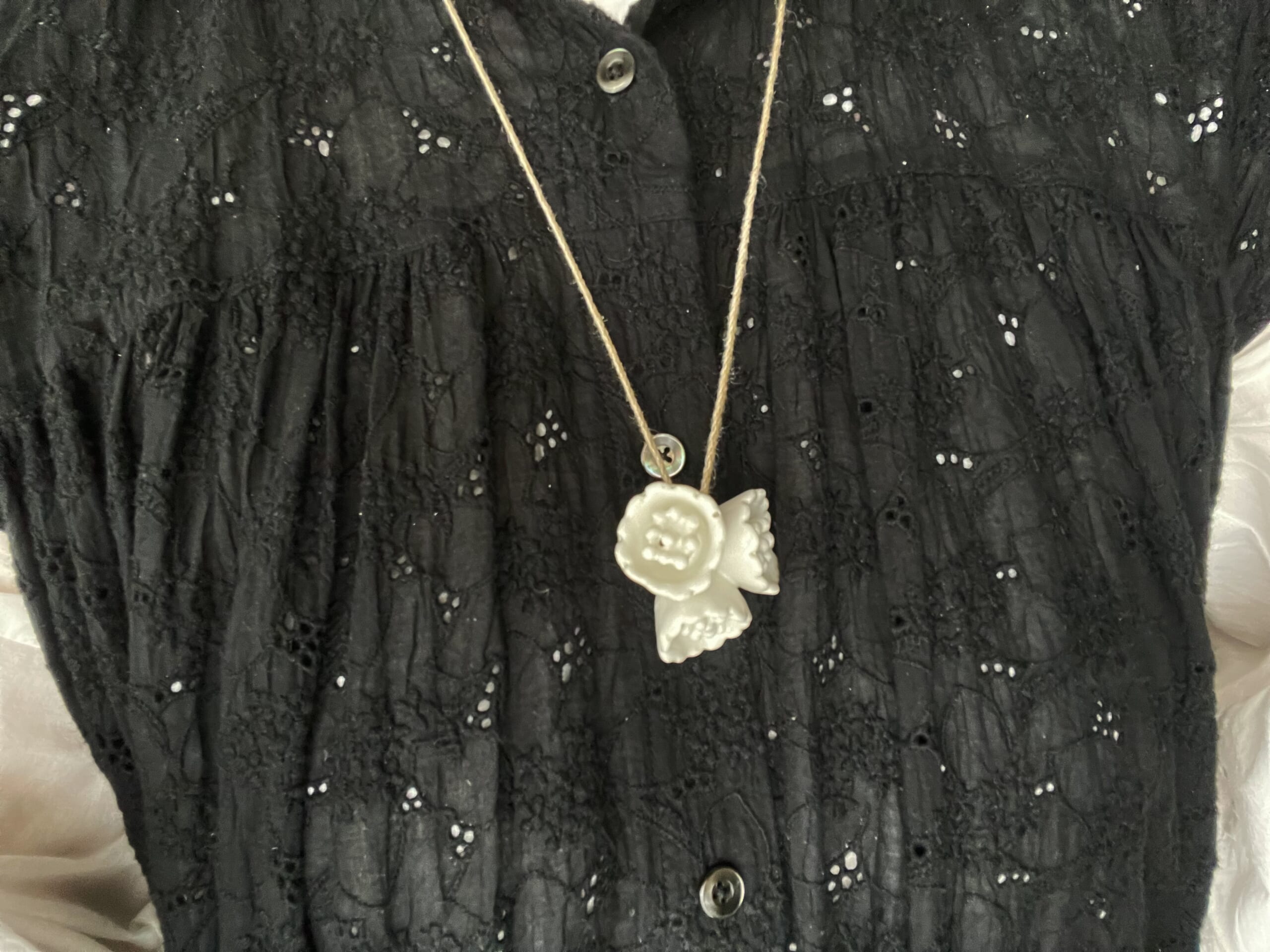 Sa-Rahの黒の総刺繍ワンピースの上に石木文さん作陶の白いお花の陶のペンダントを合わせた写真